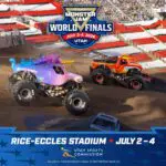 Two brightly colored monster trucks barrel around a dirt track during a Monster Jam World Finals race at Rice-Eccles Stadium, Utah, with the event logo overhead.