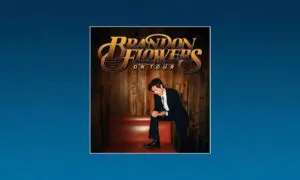 Brandon Flowers On Tour poster featuring a man in a suit posing on a red bench against wooden panel backdrop.