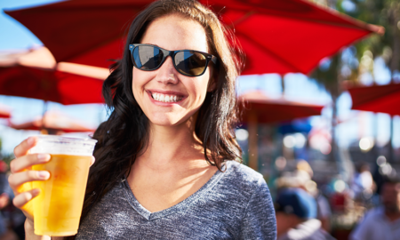 woman smiling while holding a beer