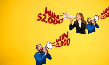 Three people cheer with megaphones as bold red 'Win $2,000' text circles across a bright yellow background.